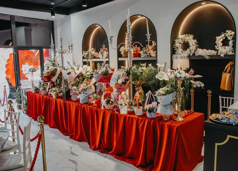 Dugačak sto sa izloženim cvetnim aranžmanima u cvećari Velure